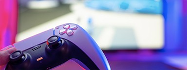 电视上游戏背景模糊的 PlayStation 5 控制器特写镜头